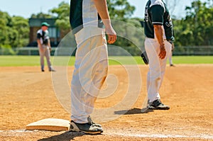 Baseball game, runner on the third base is watching the pitcher and getting ready to run to home plate and score