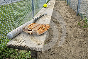 Baseball bat glove and balls on a wood bench in a park