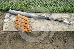 Baseball bat and glove on a wood bench