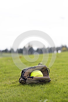 Baseball glove and yellow ball on park grass