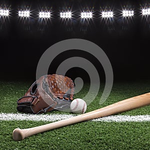 Baseball mitt ball and bat at night under stadium lights