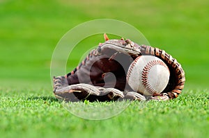 Baseball in mitt on green grass