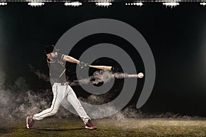 Baseball player with bat taking a swing on grand arena. Ballplayer on dark background in action.