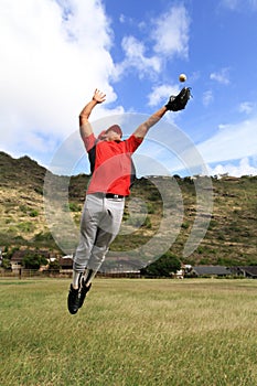 Baseball player jumps high to catch the ball