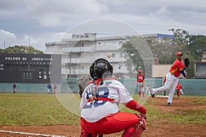 Baseball player stands at home plate, ready to swing the bat, while other players on diamond field