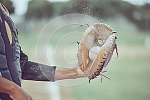 Baseball, sports and catch with a man athlete catching a ball at a game on a field or grass pitch. Fitness, health and