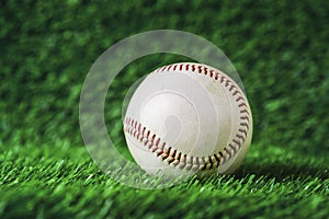 Baseball used put on green grass background.