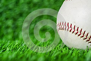 Baseball used put on green grass background.