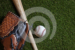 Baseball and wood bat with mitt on grass field overhead view