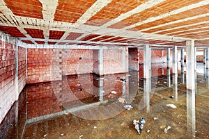 The basement of a building under construction filled with dirty flood water