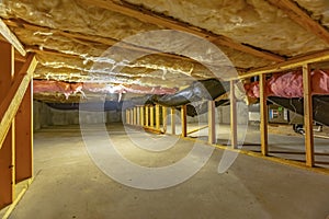 Basement or crawl space with upper floor insulation and wooden support beams photo