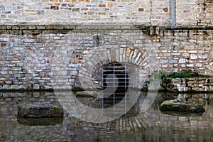 The basement curtained window of an ancient building is reflected in the water