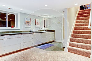 Basement with staircase, white cabinets for storage.