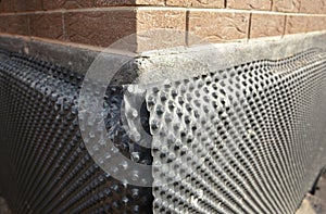 Basement waterproofing outdoors. Installation of a dimpled waterproofing membrane on the exterior basement foundation wall