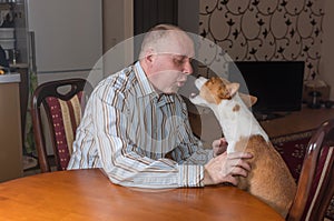 Basenji dog having hard conversation with master sitting at the table