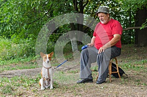 Basenji dog sitting on the ground waiting till its senior master finish resting and active play with lovely dog