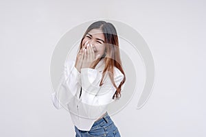 A bashful and happy young woman looking at the camera with one hand covering her mouth. Isolated on a white background