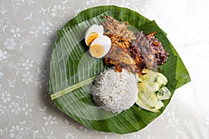 Basic authentic simple nasi lemak on banana leaf with sambal, anchovis and eggs photo