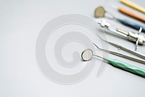 Basic dentist tools on light blue background: dental probe, gross-mayer clamp, dental mirror and explorer. Dental