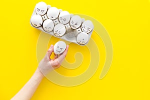 Basic emotions concept. Faces drawn on eggs. Happy, smile, sad, angry, in love. Yellow background top view copy space