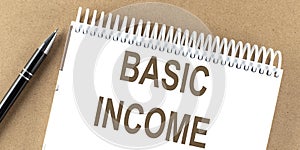 BASIC INCOME text on a notepad with pen, business concept