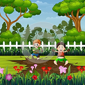 Happy kids playing a mud puddle in the park