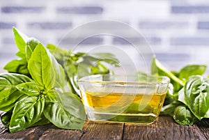 Basil oil and fresh herbs on wooden table
