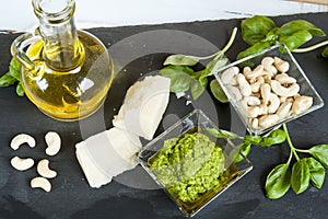 Basil pesto fresh basil leaves parmigiano cheese olive oil and cashew seeds on black stone background