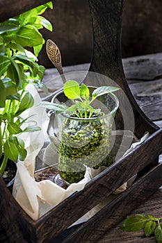 Basil pesto sauce in glass on wooden table.