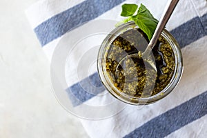 Basil pesto sauce in spoon on kitchen towel, above