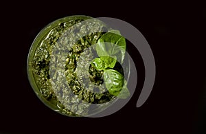 Basil sauce served in a plate and isolated in dark background