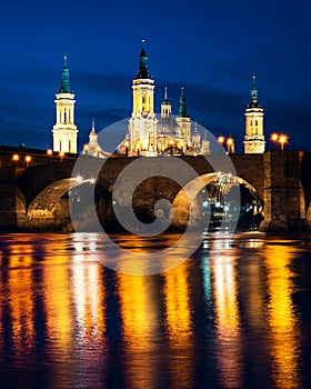 Basilica del Pilar and Puente de Piedra reflected in the Ebro river during the blue hour in Zaragoza, Spain
