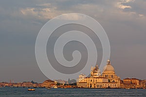 Basilica di Santa Maria della Salute at orange colors reflected on the water surface, Venice, Italy