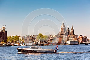 The Basilica of Saint Nicholas Sint-Nicolaasbasiliek, skyline and river with boats and ships during summer sunny day in Amsterdam