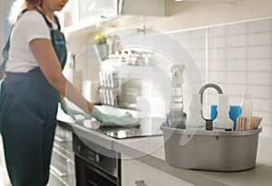 Basin with cleaning supplies on table and professional janitor