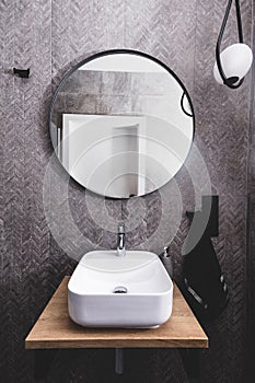 Basin and round mirror in a modern new luxury bathroom