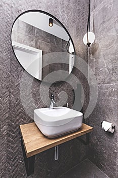 Basin and round mirror in a modern new luxury bathroom