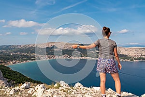 Baska - Active woman on scenic hiking trail with panoramic aerial view of idyllic lagoon in coastal town Baska