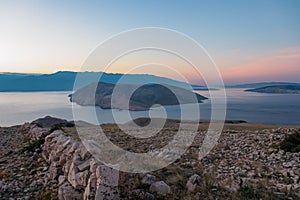 Baska - Panoramic sunrise view of deserted island Prvic seen from idyllic hiking trail near coastal town Baska