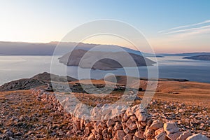 Baska - Panoramic sunrise view of deserted island Prvic seen from idyllic hiking trail near coastal town Baska