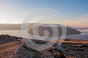 Baska - Panoramic sunrise view of deserted island Prvic seen from idyllic hiking trail near coastal town Baska