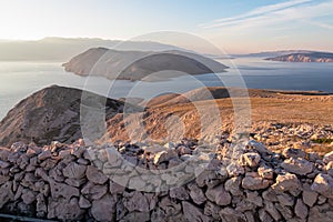 Baska - Panoramic sunrise view of deserted island Prvic seen from idyllic hiking trail near coastal town Baska