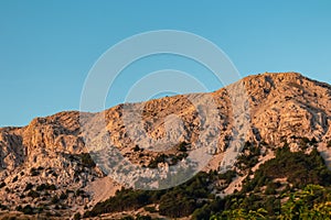 Baska - Panoramic view during sunrise of majestic mountains with massive rock formation in coastal town Baska, Krk Otok