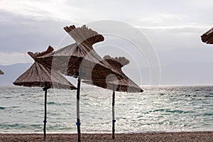 Baska - Straw umbrellas on idyllic pebble beach in tourist resort town Baska, Krk Otok, Primorje-Gorski Kotar, Croatia, Europe