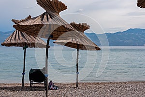 Baska - Straw umbrellas and loungers on idyllic pebble beach in resort town Baska, Krk Otok, Primorje-Gorski Kotar, Croatia