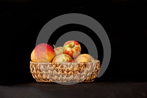 a basket of apples on a black background with a black background behind it and a black background behind it