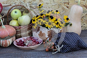 a basket of apples, a bouquet of yellow flowers, a plate with viburnum berries, a bag of rose hips and pumpkins
