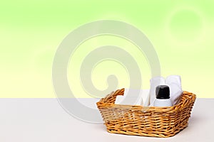 Basket with bath accessories such as soap bars, Cream and cosmetic tissues for body care on a white table over green background