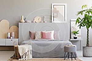 Basket with blanket and stool in front of bed in grey bedroom in