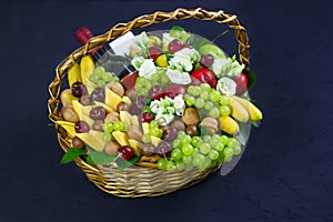 Basket with cheese, wine, grapes and fruits